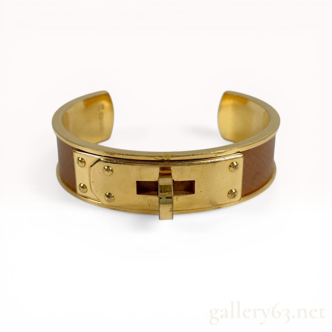 Hermes Kelly Gold-Plated and Brown Leather Cuff Bracelet: Hermes Kelly cuff bracelet featuring a brown leather inlay and gold-plated metal. The wide band is centered with a signature Kelly turn-lock closure flanked by four raised circular studs. The interior