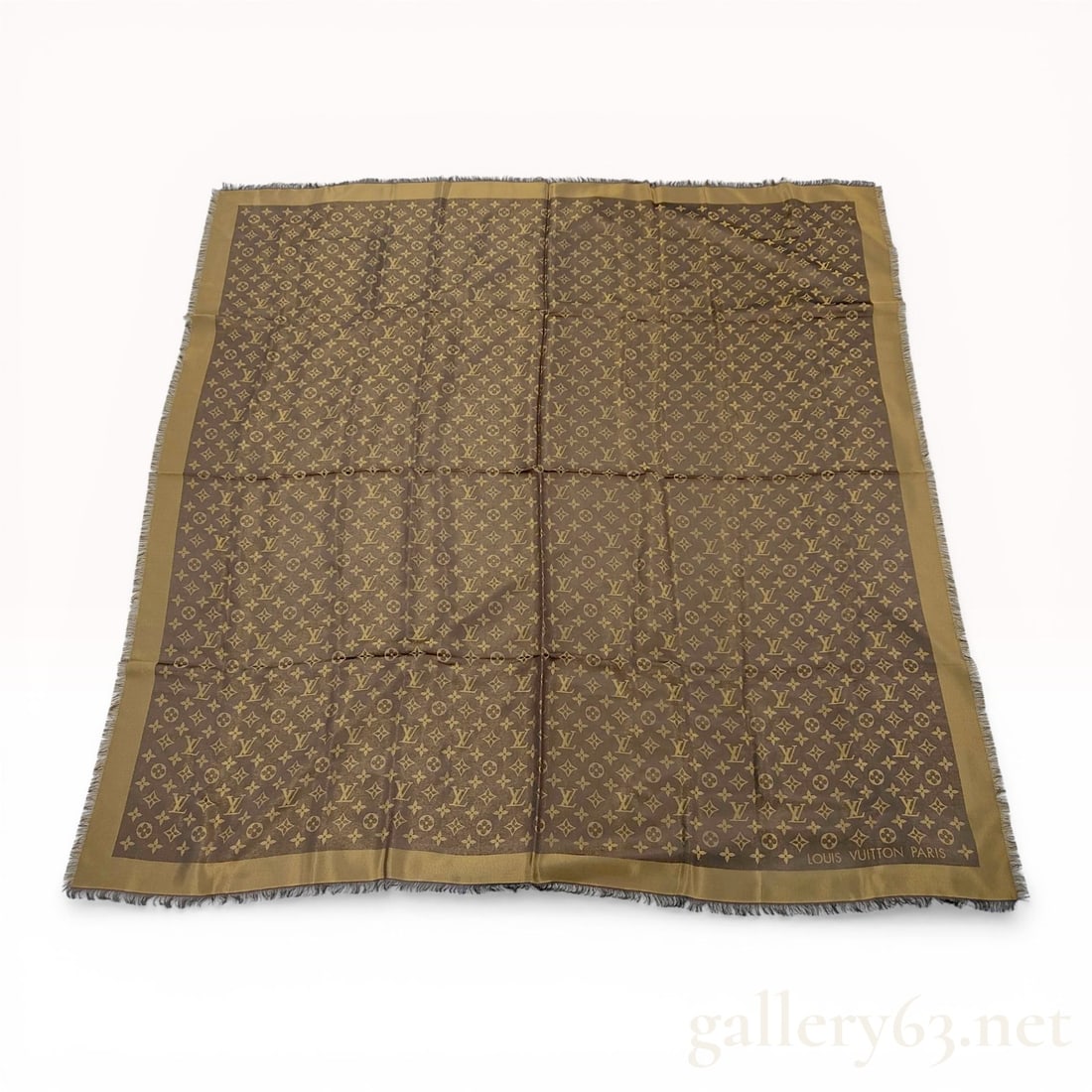 Louis Vuitton Monogram Shine Shawl in Bronze: Louis Vuitton Monogram Shine shawl in a bronze colorway, model M75122. The square shawl features an all-over jacquard-weave Monogram pattern with a metallic sheen and fringe edges. Constructed from a