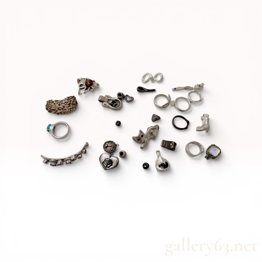 An Assortment of Silver-Toned Artisan and Novelty Costume Jewelry: A collection of contemporary artisan and mid-to-late 20th-century novelty jewelry and decorative components. The group features a wide open-work textured ring, a turquoise-colored cabochon ring, a cat
