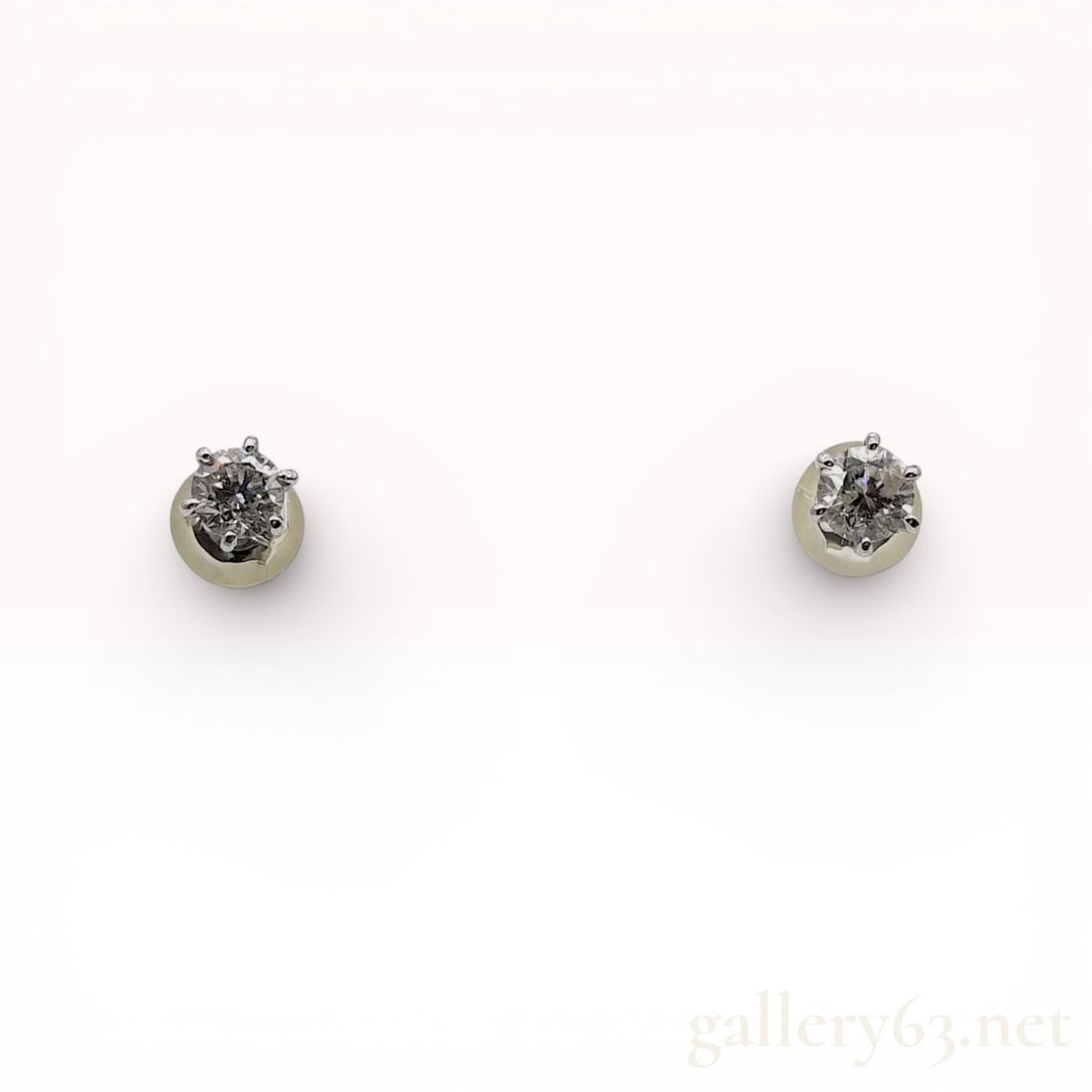A Pair of Sterling Silver and Diamond Stud Earrings: A matched pair of sterling silver stud earrings featuring round brilliant cut diamonds. Each stone is secured in a six-prong crown setting. The earrings utilize post backings with butterfly tension cl