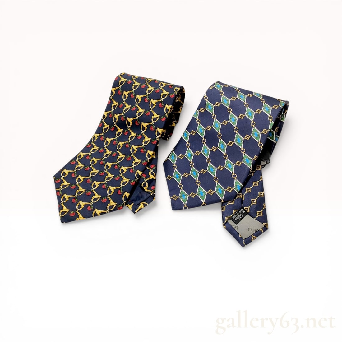 Two Designer Silk Neckties, Celine and Fendi: Two designer silk neckties by Celine and Fendi. The Celine tie features a navy blue ground with a repeating novelty pattern of golden horsebits and red raspberries, marked Made in Spain. The Fendi tie