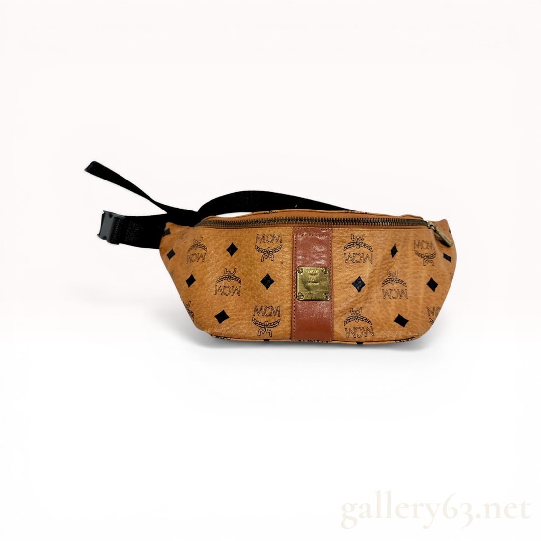 MCM Cognac Visetos Monogram Belt Bag: MCM belt bag crafted from signature cognac Visetos coated canvas featuring a repeating black laurel monogram and leather trim. The bag is designed with a single zippered main compartment, gold-tone br