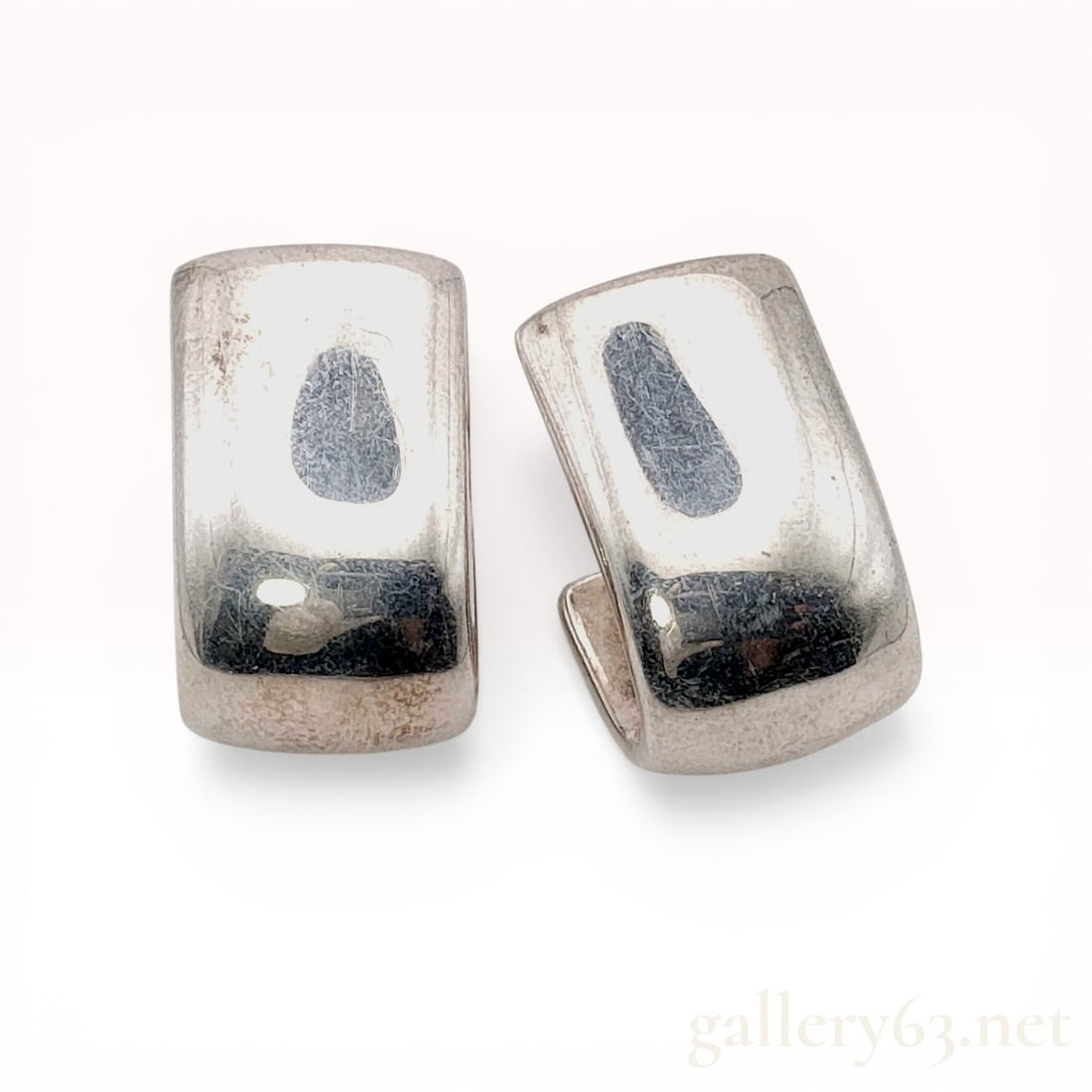 A Pair of Philippe Audibert Silver-Tone J-Hoop Earrings: A matched pair of modern J-hoop stud earrings by Philippe Audibert, Paris. The earrings feature a wide, rectangular profile in a minimalist curved form crafted from silver-tone metal. Each earring is