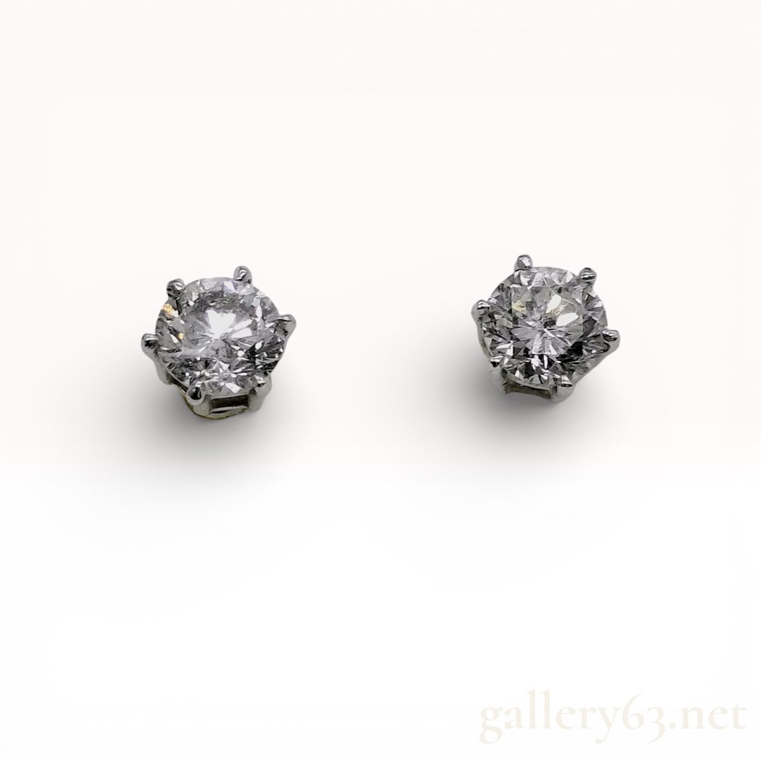 A Pair of Platinum Stud Solitaire 1.40/1.50 2.90ctw Natural Diamond Earrings: A matched pair of platinum stud earrings featuring two round brilliant cut near-colorless diamonds. Each stone is secured in a six-prong basket setting and features threaded screw-back posts with plat