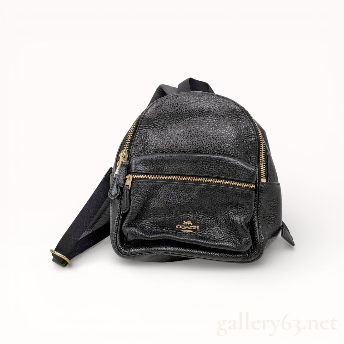 Coach Black Pebbled Leather Backpack: Coach pebbled leather backpack, contemporary. The bag features a dual-zip main compartment, a front zippered pocket, and a black nylon back panel with adjustable textile straps. It is finished with go