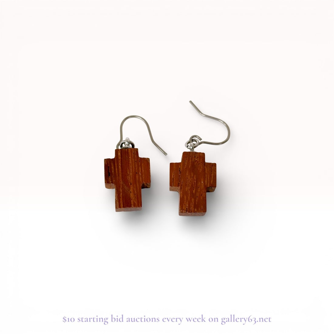 A Pair of Carved Wood Cross Dangle Earrings with Sterling Silver Accents: A matched pair of dangle earrings featuring carved wooden crosses with a visible open grain. The charms are suspended from silver-toned metal French hook ear wires. Each earring contains an inset meta