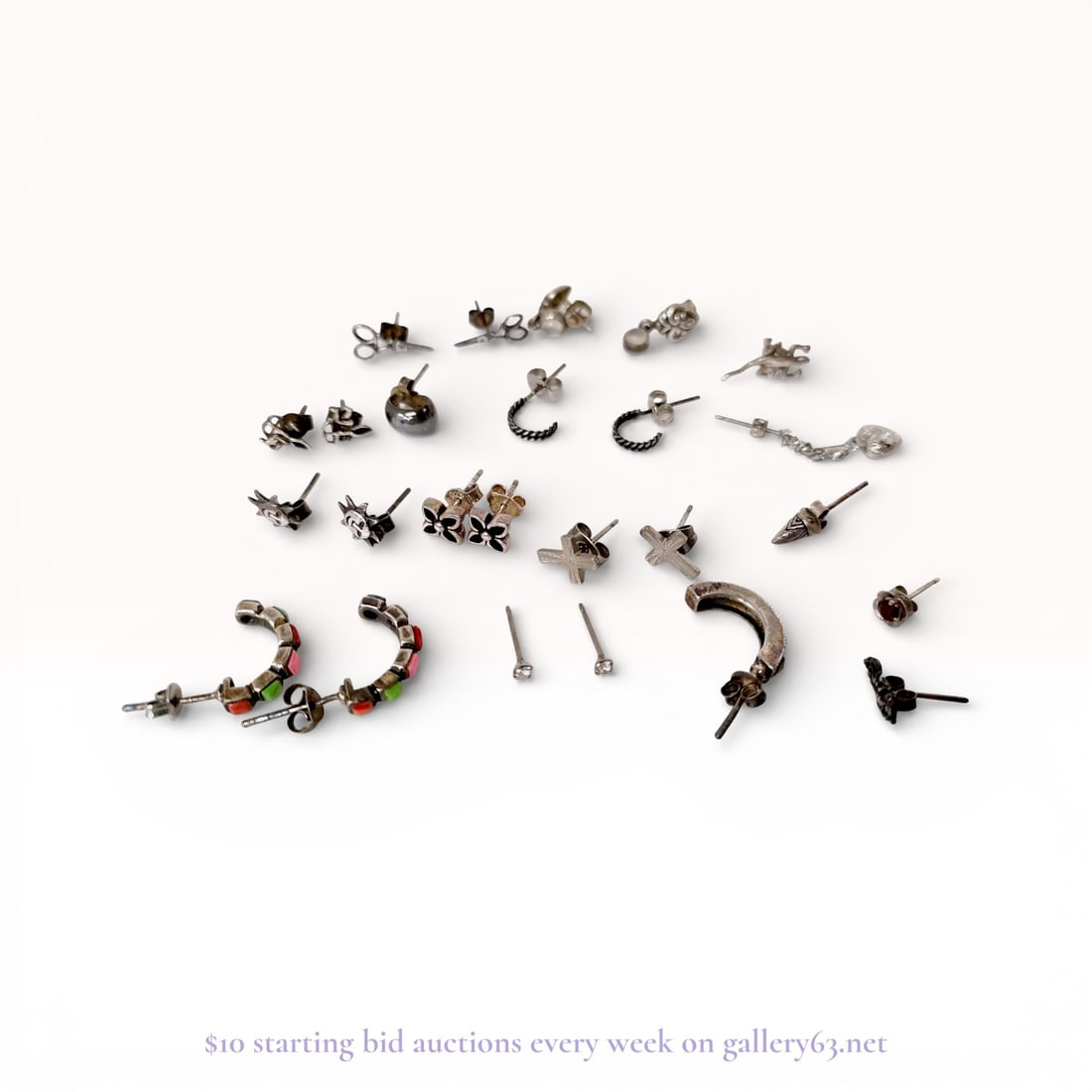 An Assortment of Sterling Silver Earrings: An assortment of sterling silver and silver-tone jewelry earrings featuring various post and hoop styles. The collection includes matched pairs with motifs of scissors, suns, crosses, and cherubs, alo