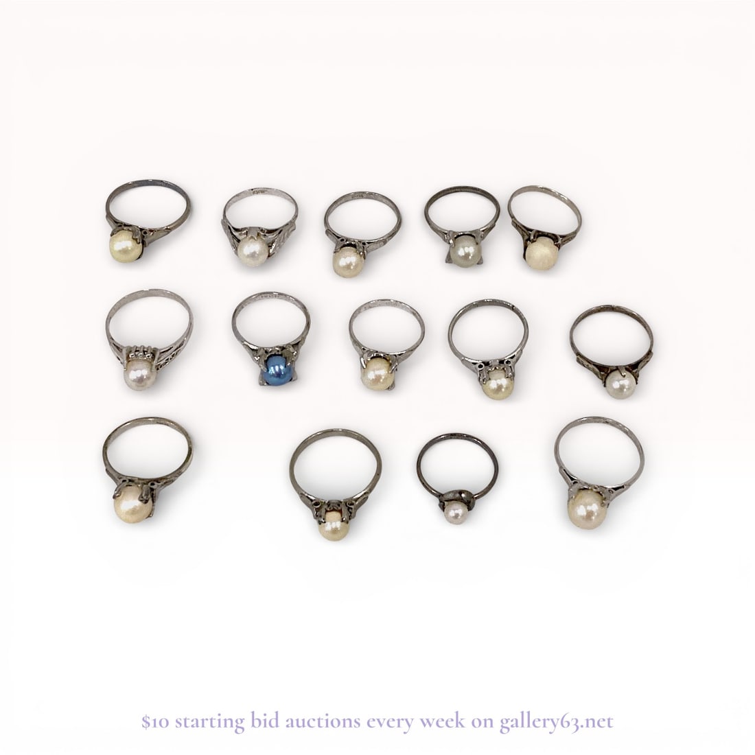 Thirteen Mid Century Pearl and Sterling Silver Solitaire Rings: A collection of thirteen solitaire rings featuring single pearls set in sterling silver bands. The lot includes twelve white to cream-colored pearls and one blue pearl, set in various styles such as f