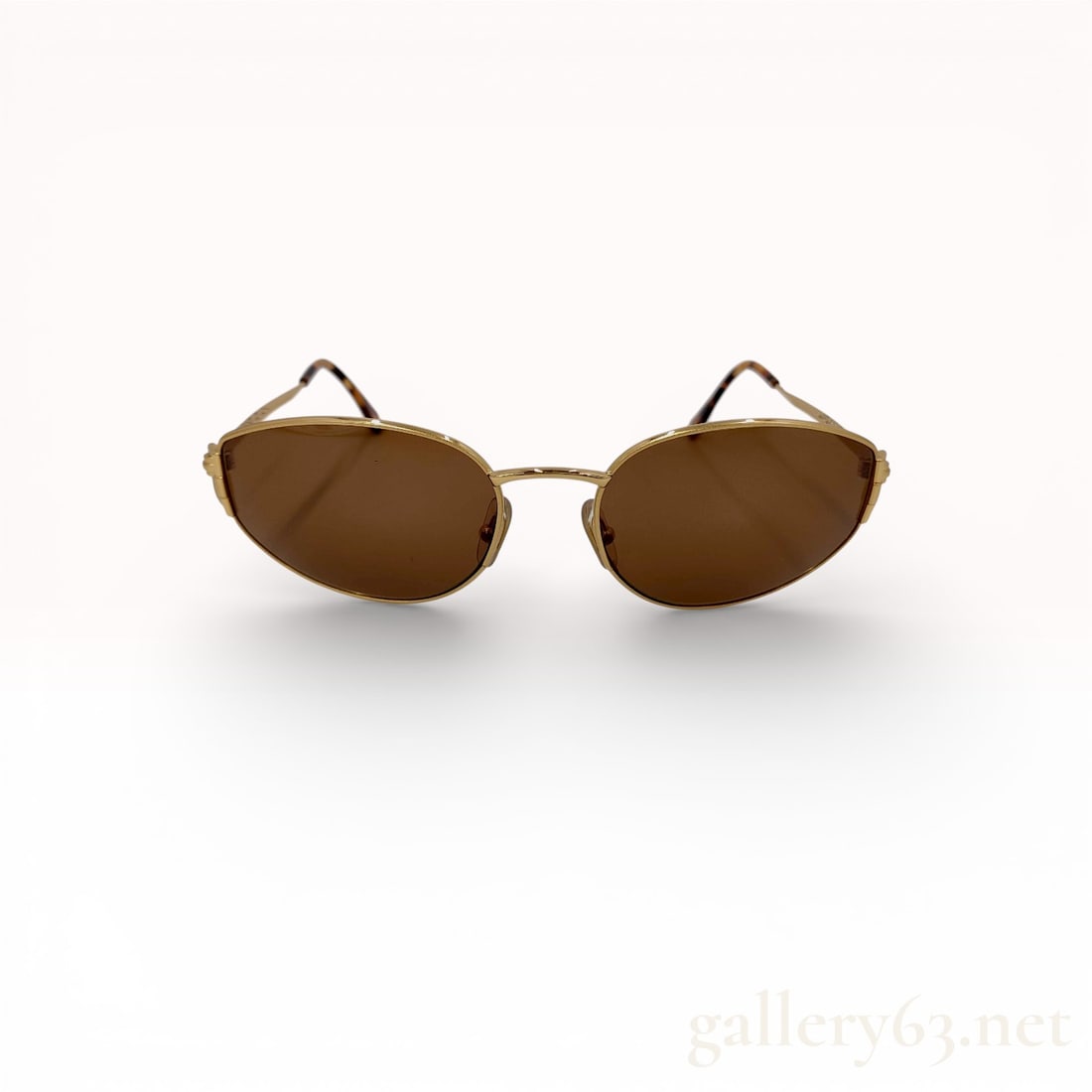 Gucci Gold-Tone Metal Oval Sunglasses with Horseshoe Hinges: Gucci gold-tone metal oval sunglasses manufactured in Italy. The design features brown-tinted lenses, decorative horseshoe-style hinges, and tortoise-patterned acetate ear tips. Interior temple is mar