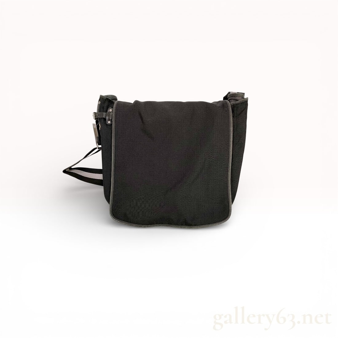Bally Black Textile Messenger Bag: Bally messenger-style bag featuring a black heavyweight textile body with leather-style piping and trim. The design includes a front flap closure and an adjustable webbed shoulder strap with a charact