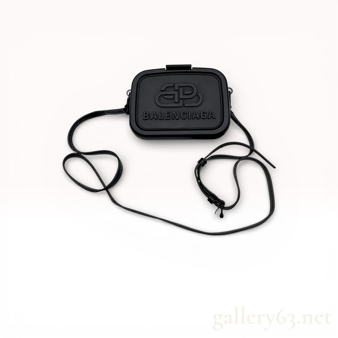 Balenciaga Black Plastic Mini Lunch Box Case Crossbody Bag: Balenciaga Lunch Box crossbody bag featuring a molded matte black hard-shell plastic body. The front face is detailed with an embossed interlocking BB logo and the Balenciaga brand name. The bag is de