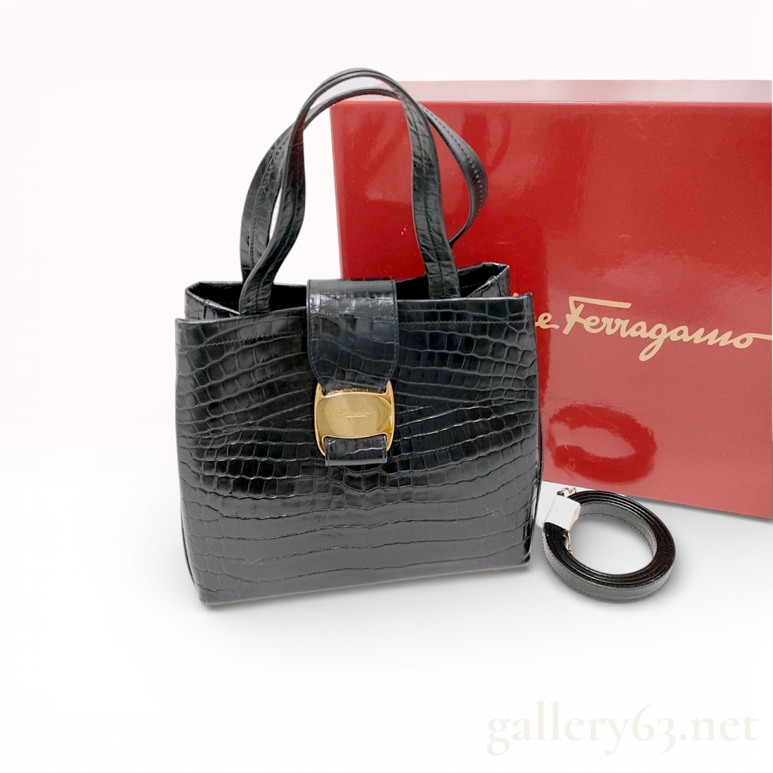 Salvatore Ferragamo Black Crocodile-Embossed Leather Top Handle Handbag: Salvatore Ferragamo structured top handle handbag in black crocodile-embossed leather. The design features dual flat top handles, a front decorative strap with a gold-tone buckle incised with the Ferr