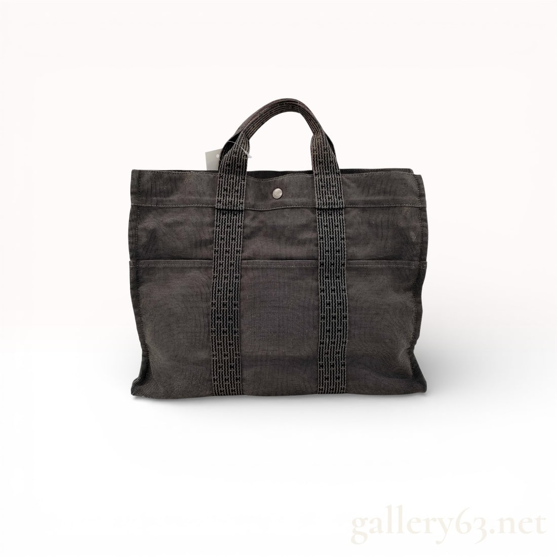 Hermes Herline GM Canvas Tote Bag: Hermes Herline GM tote bag in charcoal gray polyester canvas. The exterior features six slip pockets and vertical woven straps with a repeating H logo motif. The interior contains a zippered pocket an