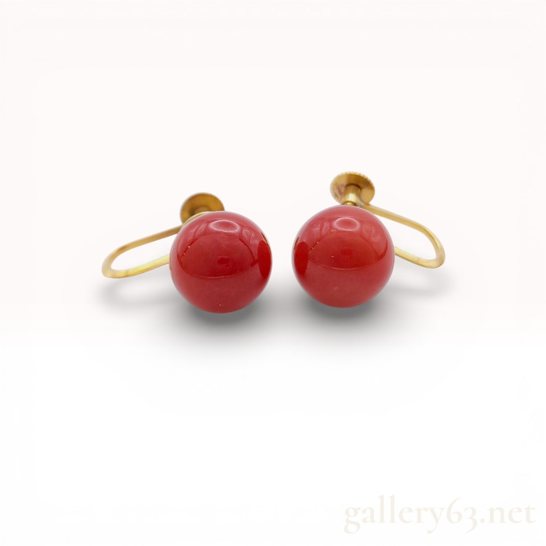 A Pair of 18K Yellow Gold and Antique Red Coral Bead Screw-Back Earrings: A matched pair of vintage screw-back earrings featuring 18K yellow gold and antique red coral. Each earring contains a 10mm spherical, opaque red coral bead with a high polish and deep red color. The