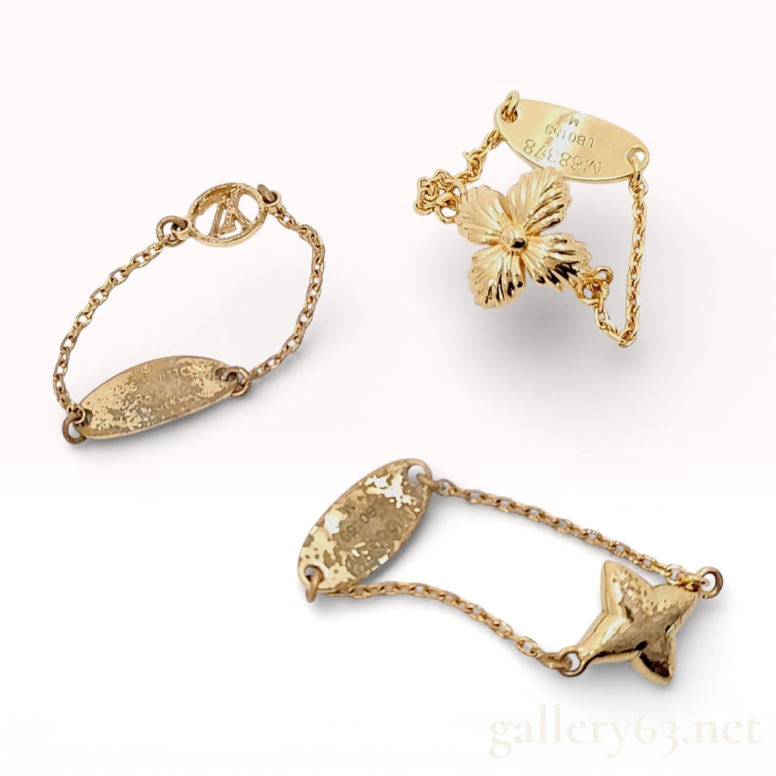 Three Louis Vuitton Blooming Monogram Chain Rings: Louis Vuitton Blooming ring set, model M68378, featuring three individual chain-link rings in gold-toned metal. Each piece includes a distinct motif: a textured four-petaled flower, a polished star mo