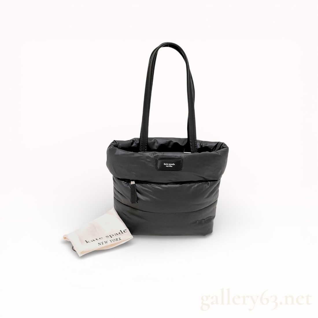 Kate Spade New York Puffed Puffy Small Tote: Kate Spade New York Puffed Puffy small tote bag in black quilted nylon. The exterior features dual rounded leather shoulder straps, a horizontal zippered front pocket, and a rectangular logo plaque. T