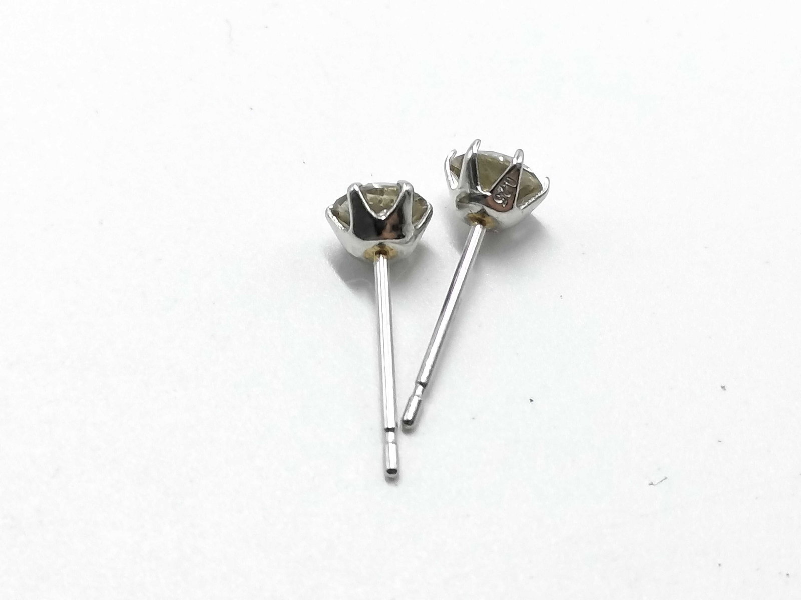 A Pair of Light Brown Diamond and Pt900 Platinum Stud Earrings: A matched pair of diamond stud earrings featuring round brilliant-cut stones in a light yellowish-brown hue. Each stone is set in a six-prong platinum basket and is approximately 0.25 carats based on 