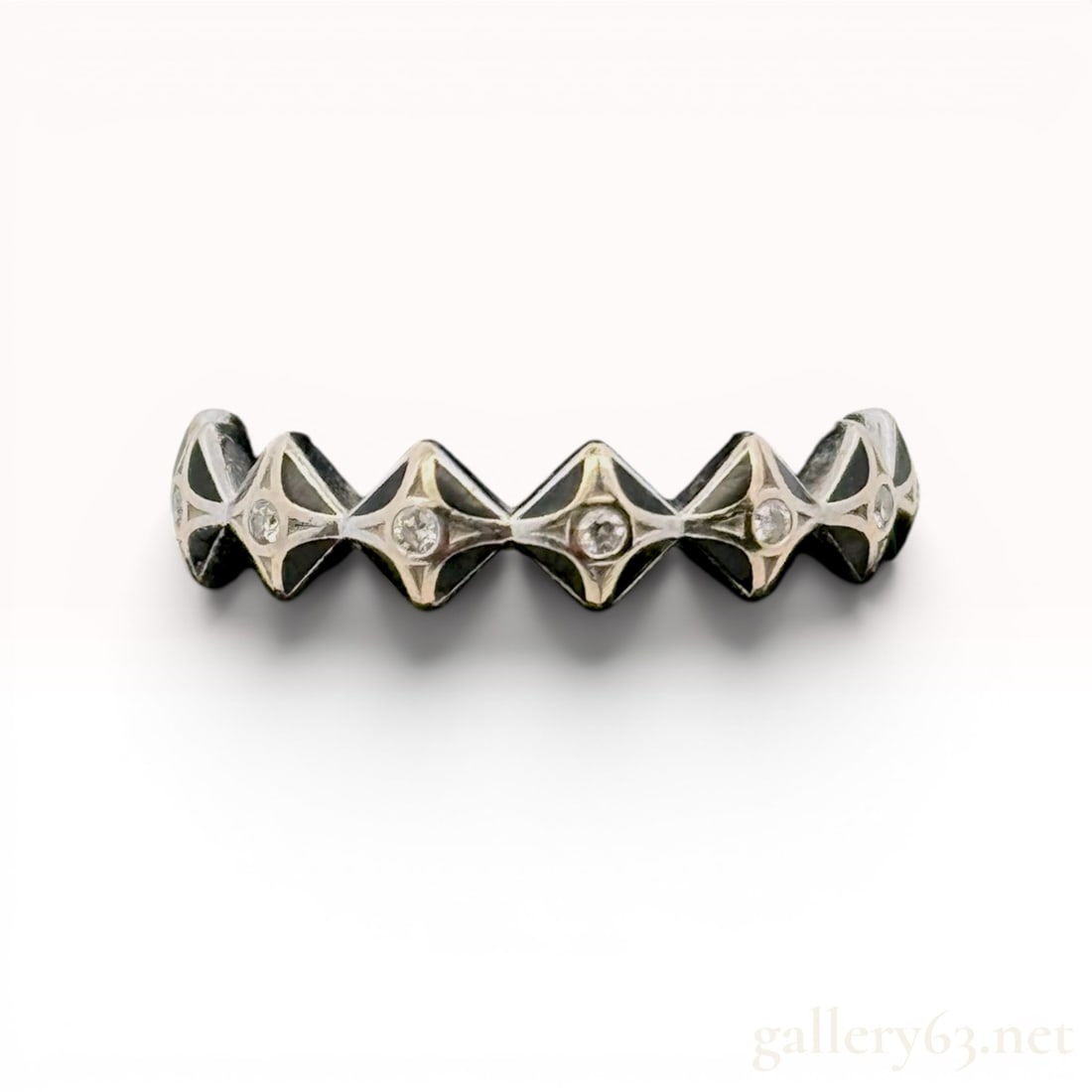 18 Karat White Gold, Diamond, and Enamel Geometric Band Ring: 18 karat white gold and black enamel geometric band ring featuring round brilliant-cut diamonds totaling .10 carats. The contemporary design is composed of raised rhomboid stations with star-set diamo
