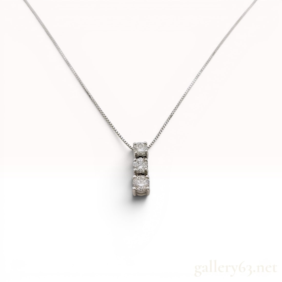 Platinum Three-Stone 1.01ctw Diamond Pendant Necklace: Three-stone diamond pendant necklace set in 850 platinum. The vertical drop pendant features three round brilliant-cut diamonds in four-prong basket settings suspended from a fine box chain. The chain