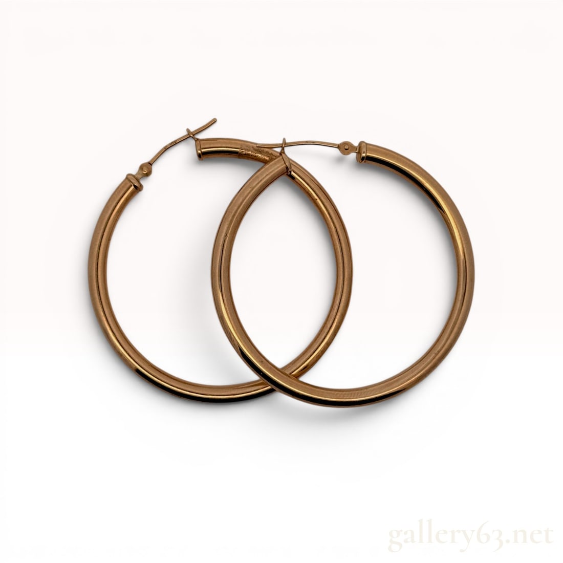 A Pair of 10K Rose Gold Polished Hoop Earrings: A matched pair of large, polished hollow tube hoop earrings crafted in 10 karat rose gold. The earrings feature hinged snap-bar closures and have a lightweight design. Each ear wire is stamped with th