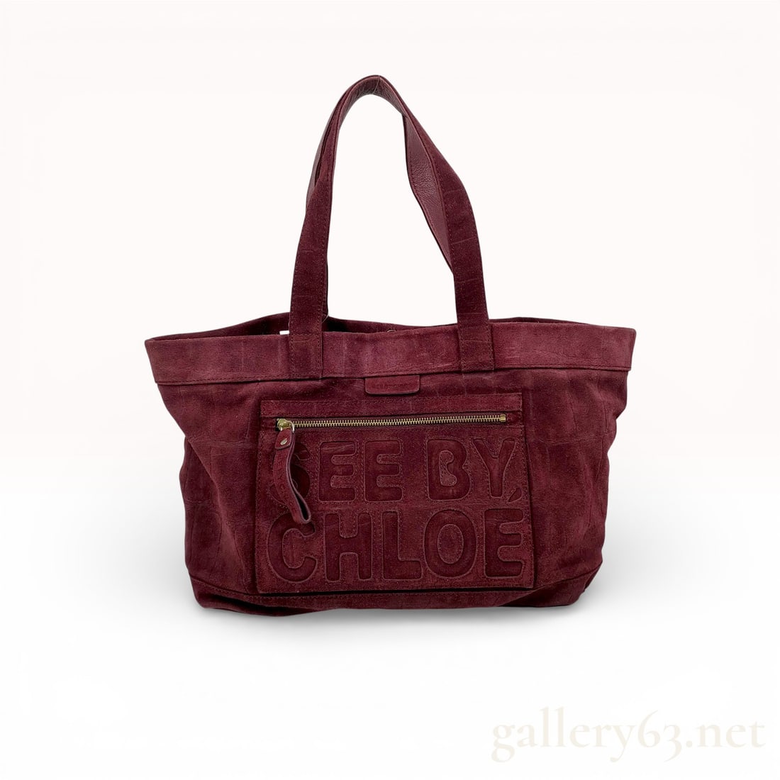 See By Chloe Burgundy Suede Textured Tote Bag: A See By Chloe tote bag constructed from burgundy suede with an embossed textured pattern. The bag features dual top handles and a large front zippered pocket with the maker name embossed in block let
