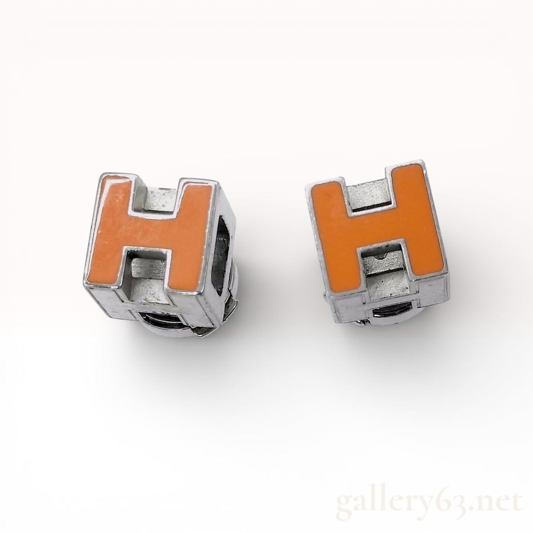 Palladium-Plated Metal Stud Earrings, Hermes Cage d'H Enamel Cubes: A pair of authentic Herm?¨s Cage d'H stud earrings featuring the iconic three-dimensional H cube design. Earrings having signature orange enamel on one side and white enamel on the other, both set in
