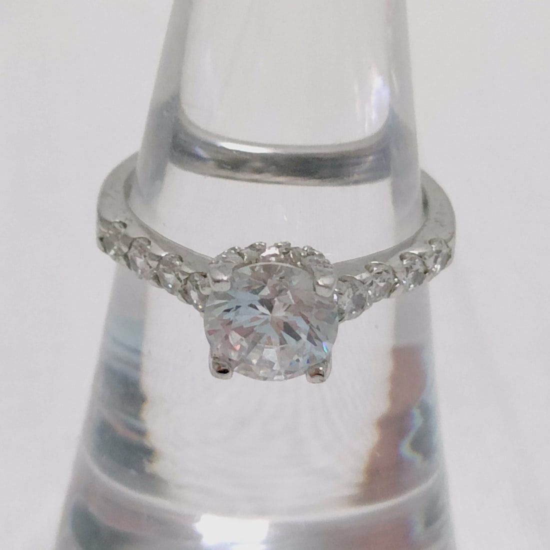 Sterling Silver Round Brilliant-Cut Solitaire Ring with Accented Shoulders: Engagement-style ring featuring a round brilliant-cut colorless stone in a four-prong basket setting surrounded by a halo of smaller accents. The shank is crafted from sterling silver with pavé