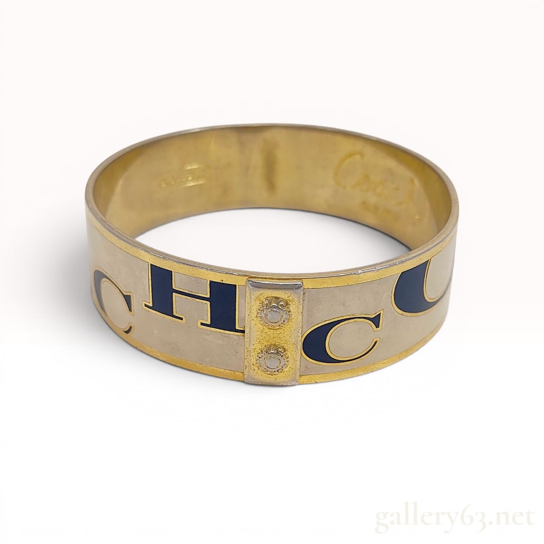 Coach Enamel and Gold-Tone Logo Bangle Bracelet: Coach gold-tone and enamel bangle bracelet, contemporary. The wide band features a cream enamel inlay decorated with navy blue serif letters spelling the brand name, accented by a raised gold-tone pla