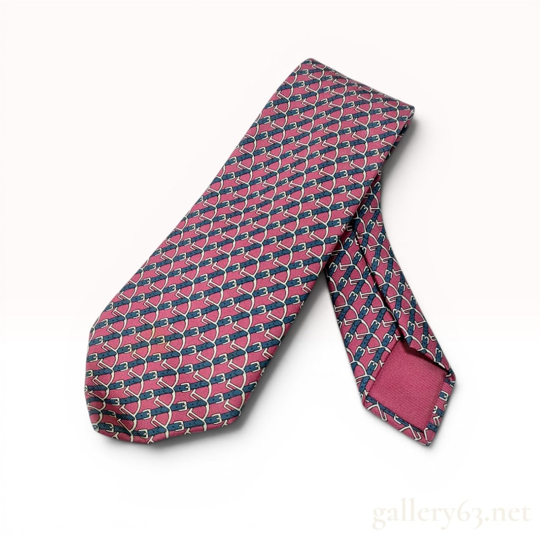 Hermes Silk Equestrian Buckle Print Necktie with Box: Hermès silk necktie featuring a repeating equestrian buckle and strap motif on a raspberry-pink ground. Hand-sewn in France from 100 percent silk with navy blue and cream accents. The reverse d