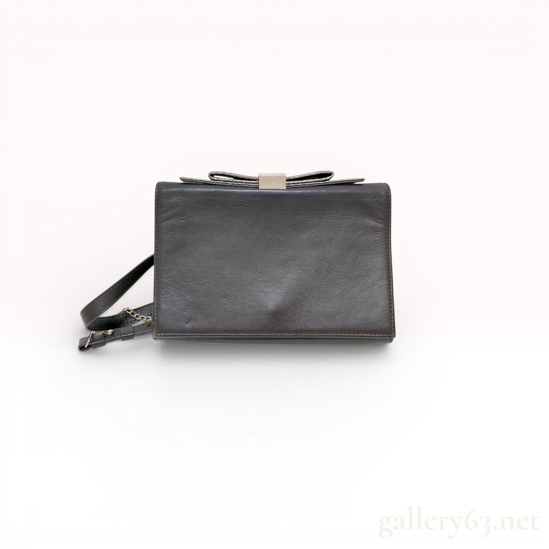 Ted Baker London Charcoal Grey Leather Bow Convertible Crossbody Bag: A Ted Baker London structured handbag constructed from charcoal grey leather. The exterior features a signature bow detail on the front flap, accented with a gold-tone metallic center piece engraved w