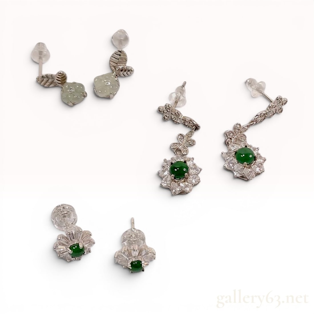 A Trio of Sterling Silver and Green Gemstone Earrings: A trio of 925 sterling silver earrings featuring assorted green stones and colorless accents in floral and leaf motifs. The collection includes a pair of leaf-design drops with pale green translucent 
