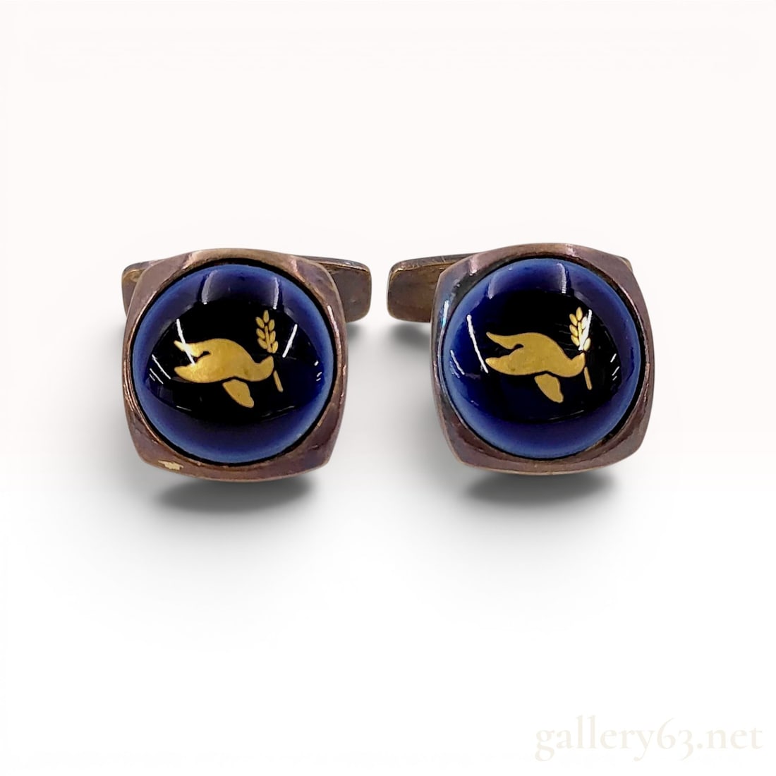 A Pair of Georg Jensen Sterling Silver and Royal Copenhagen Porcelain Dove Motif Cufflinks: Georg Jensen sterling silver cufflinks featuring Royal Copenhagen porcelain inserts, mid to late 20th century. Each cufflink displays a dark blue cabochon face decorated with a gold-toned dove and oli