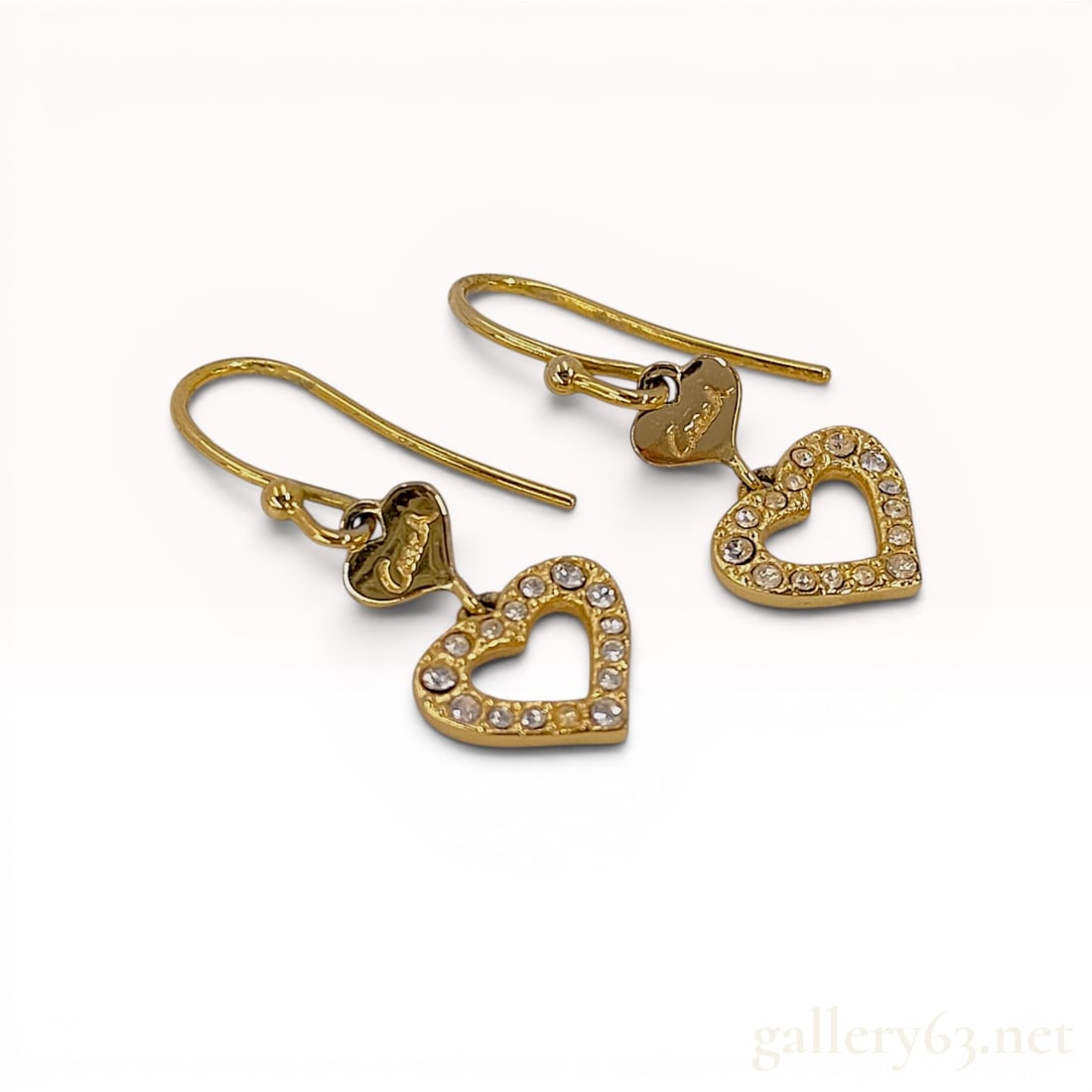 A Pair of Coach Gold-Tone Crystal Double Heart Drop Earrings: A matched pair of Coach designer costume jewelry tiered heart drop earrings. Each earring features a gold-tone French wire hook suspending a small solid heart and a larger open heart pendant pav&eacut