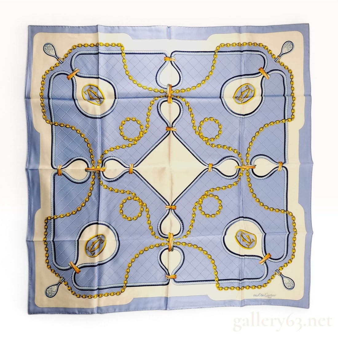 Must de Cartier Silk Scarf with Jewelry and Chain Link Motif: A square silk scarf by Cartier featuring a jewelry and equestrian-inspired pattern. The design is centered around a cream-colored diamond set against a periwinkle blue field with a cream-toned border.