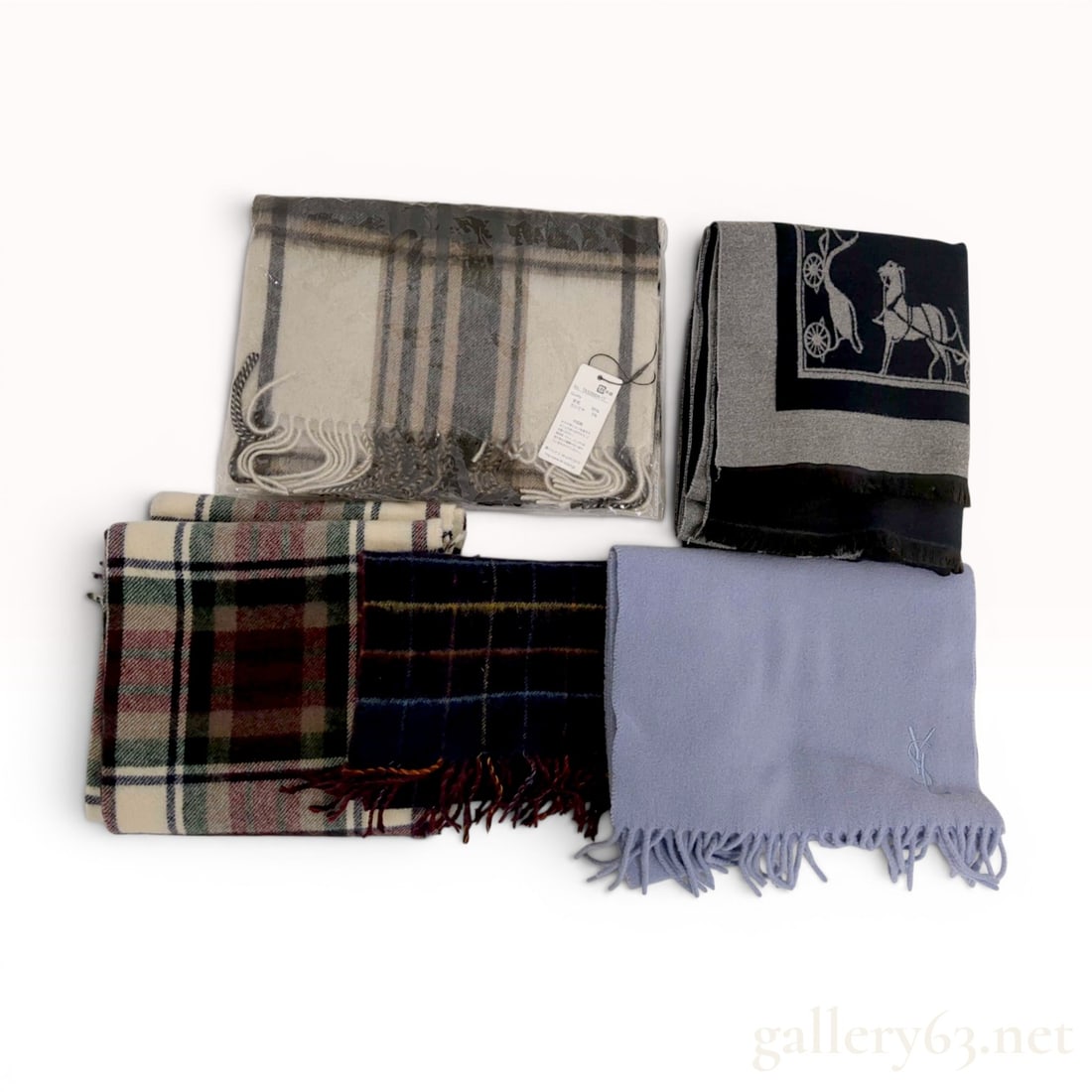 A Collection of Five Designer and Assorted Scarves including Yves Saint Laurent: A collection of five designer and assorted scarves featuring various patterns and materials including wool and cashmere blends. The group includes a solid lavender scarf with an embroidered Yves Saint