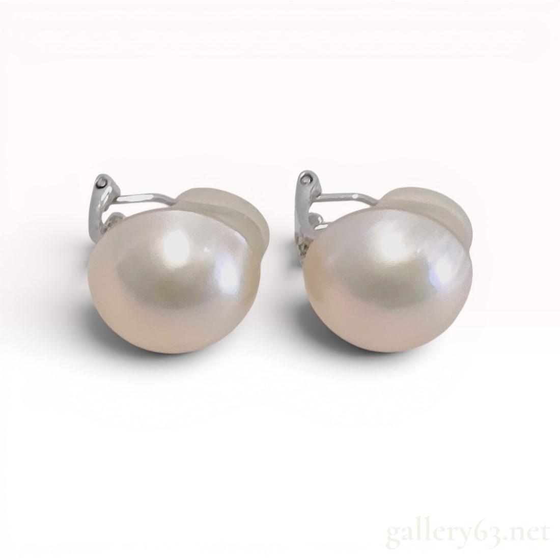 A Pair of Silver and Mabe Pearl Clip-on Earrings: A matched pair of silver clip-on earrings, each featuring a large hemispherical mabe pearl. The pearls are bezel-set and display a creamy white color with high luster. Stamped SILVER on the hinged cli