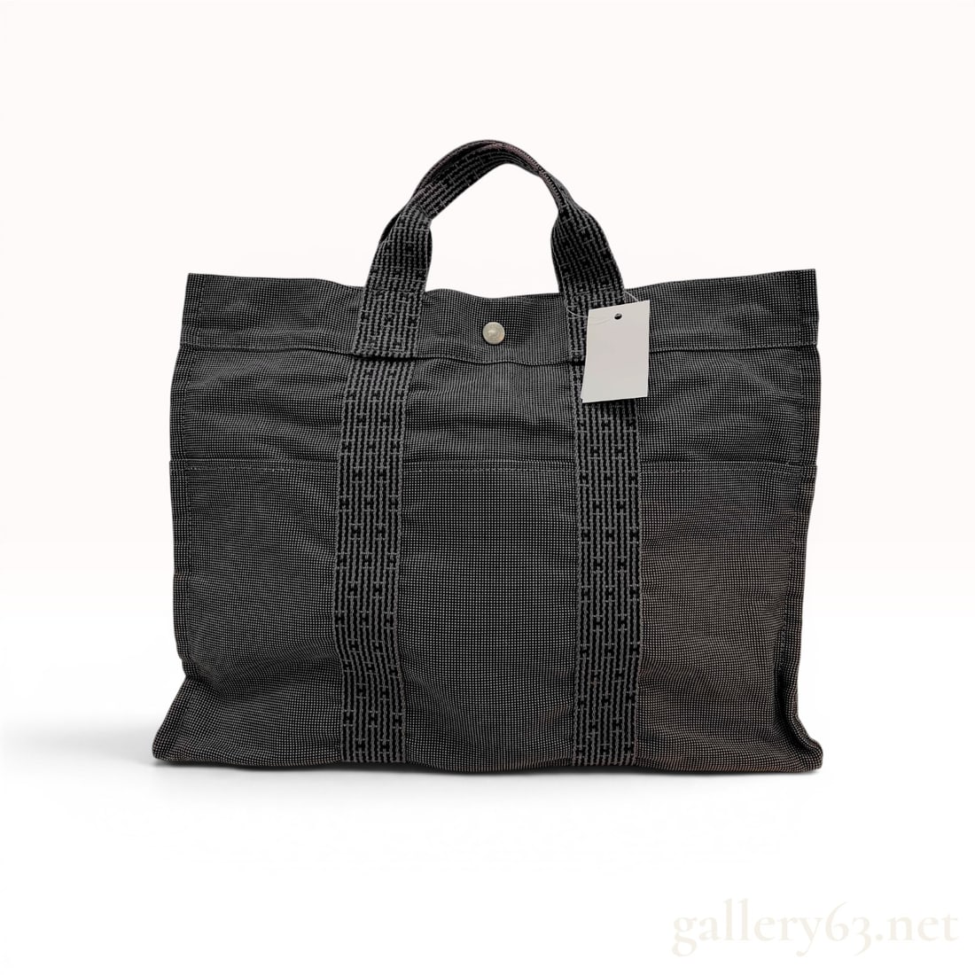 Hermes Herline GM Canvas Tote Bag: Hermès Herline GM tote bag in gray and black textured canvas. This large-scale bag features six exterior slip pockets and signature vertical webbing straps with a repeating woven H motif. The i