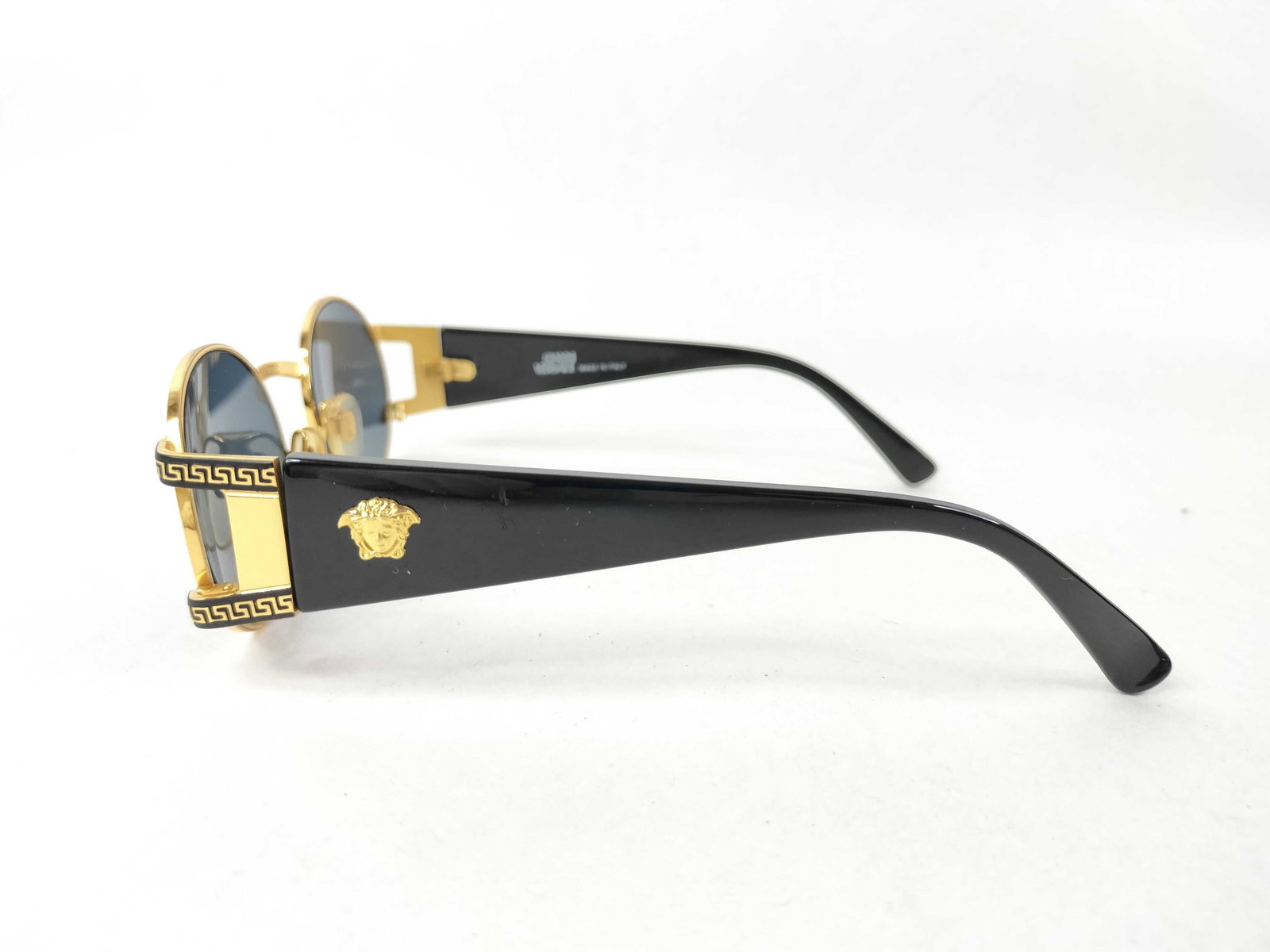 Gianni Versace MOD.S60 Vintage Oval Sunglasses: A pair of vintage Gianni Versace sunglasses, model MOD.S60, colorway COL.49L. This eyewear features dark gray-tinted oval lenses mounted in a gold-tone metal frame. The gold-tone bridge is stamped on 