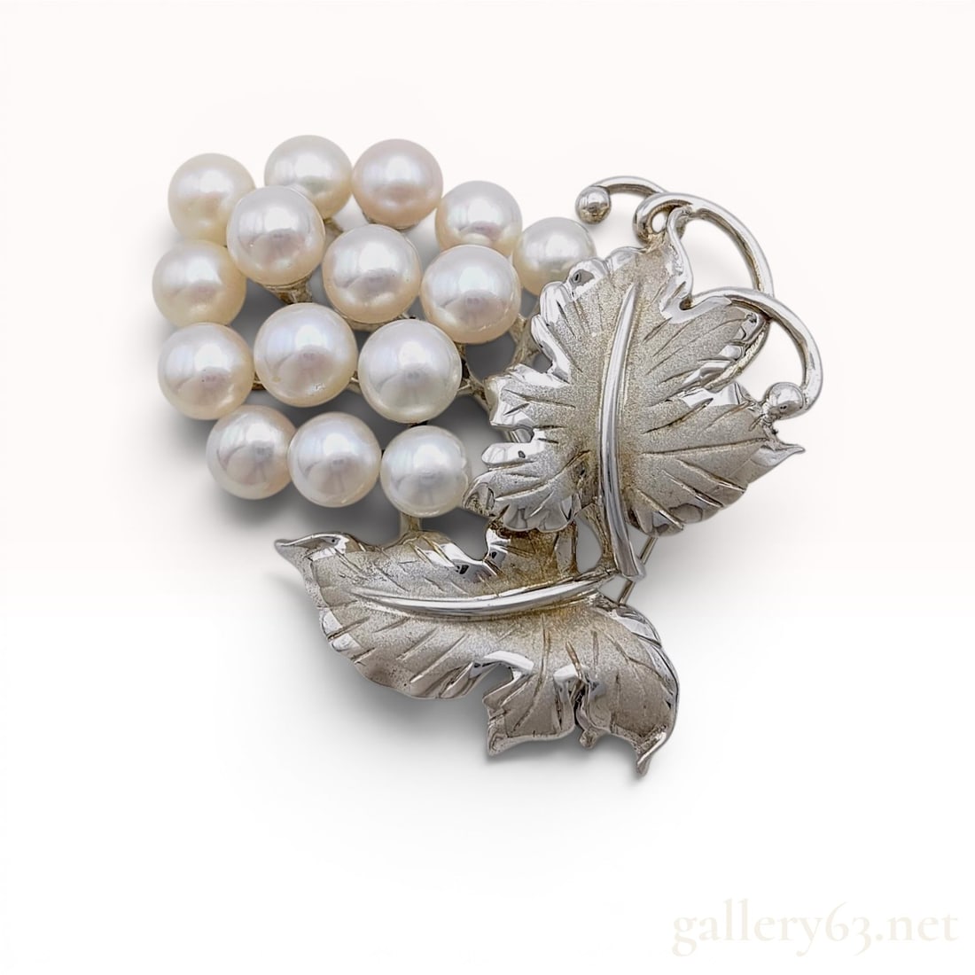Mikimoto Cultured Pearl and Silver Grape Cluster Brooch: Mikimoto cultured pearl and silver brooch designed in a grape cluster motif, mid-20th century. The piece features sixteen graduated cultured pearls with white-to-cream body color and rose overtones, i