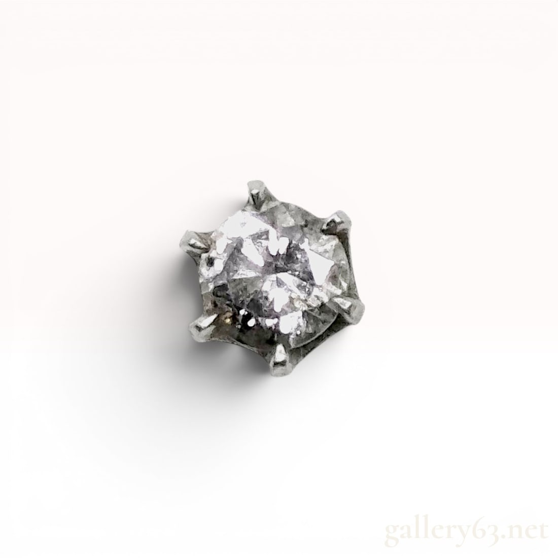 A Single Platinum and Round Brilliant-Cut Diamond Stud Earring: Single stud earring for pierced ears featuring a round brilliant-cut diamond in a six-prong basket setting. The diamond exhibits significant and visible natural dark and cloudy inclusions throughout t