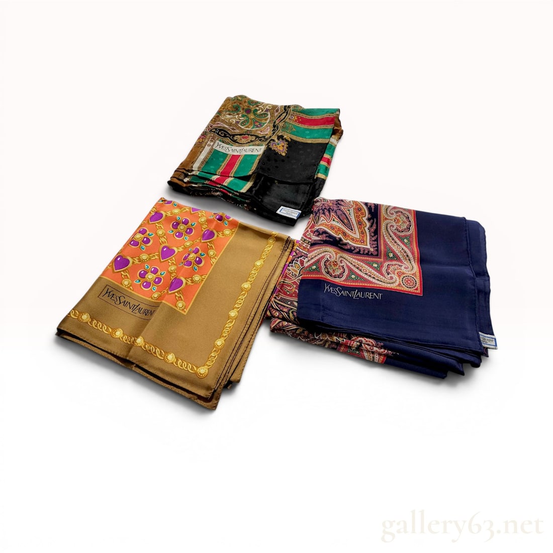 A Trio of Yves Saint Laurent Silk Scarves: Trio of vintage Yves Saint Laurent 100% silk square scarves, distributed for the Japanese market by Tokyo Kawabe Co., Ltd. The collection features a jewelry-themed pattern with gold chains and purple 