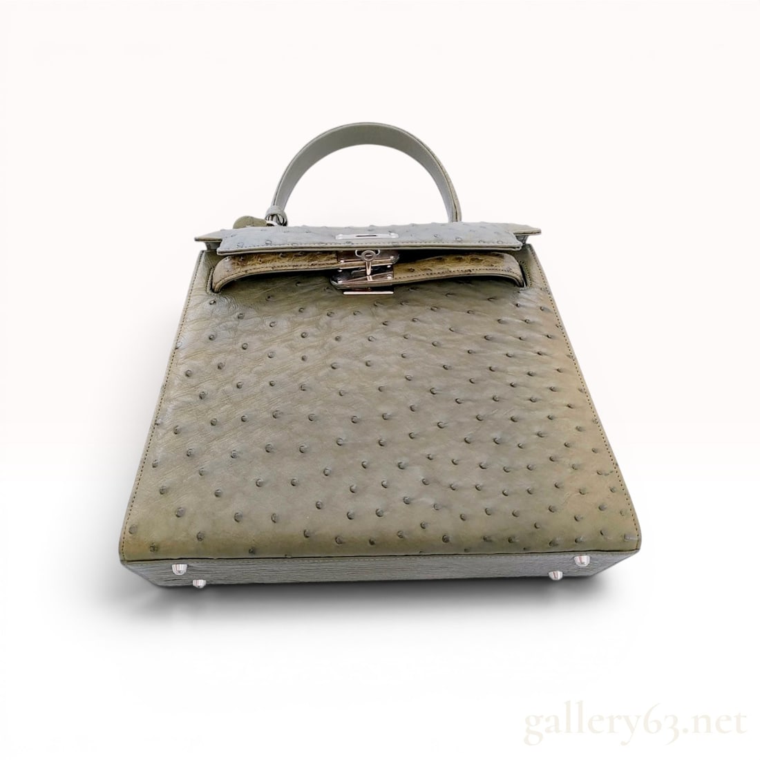Olive Green Ostrich Leather Top Handle Bag: Rodania top handle bag in a structured Kelly-style silhouette, crafted from olive green ostrich leather. The exterior features a single top handle, four protective metal feet at the base, and silver-t