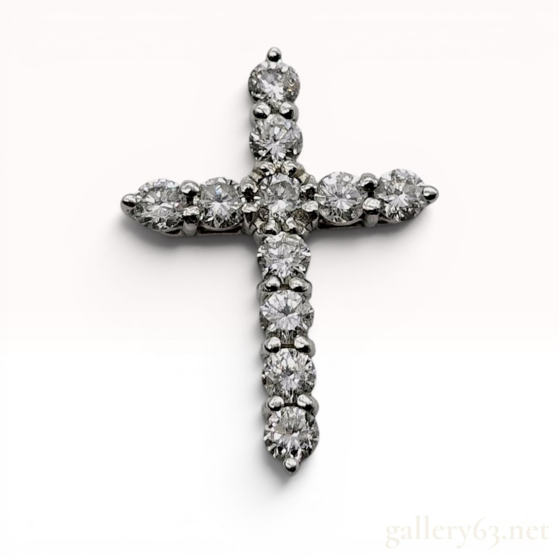 Platinum and Diamond Cross Pendant: Platinum cross pendant featuring eleven round brilliant-cut diamonds in a shared-prong basket setting. The reverse of the pendant is designed with a hidden integrated bail and is stamped with Pt900 an