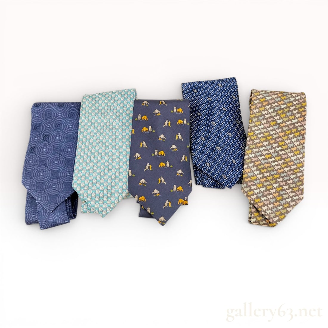 A Collection of Five Designer Silk Neckties Including Hermes, Givenchy, and Celine: A collection of five designer men's silk neckties from various high-end luxury brands. The collection features a variety of classic and whimsical patterns. Hermès Tie: Features a dense, multi-c