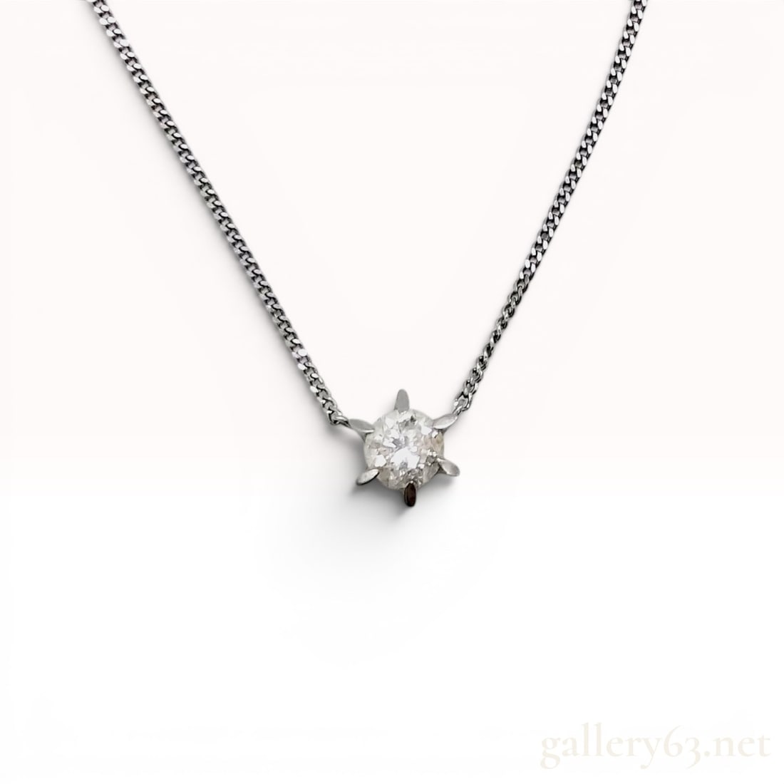 Platinum and Diamond Solitaire Pendant Necklace: Platinum and diamond solitaire pendant necklace featuring a round brilliant-cut diamond weighing approximately 0.30 carats. The gemstone is held in a six-prong star-shaped basket setting attached to a