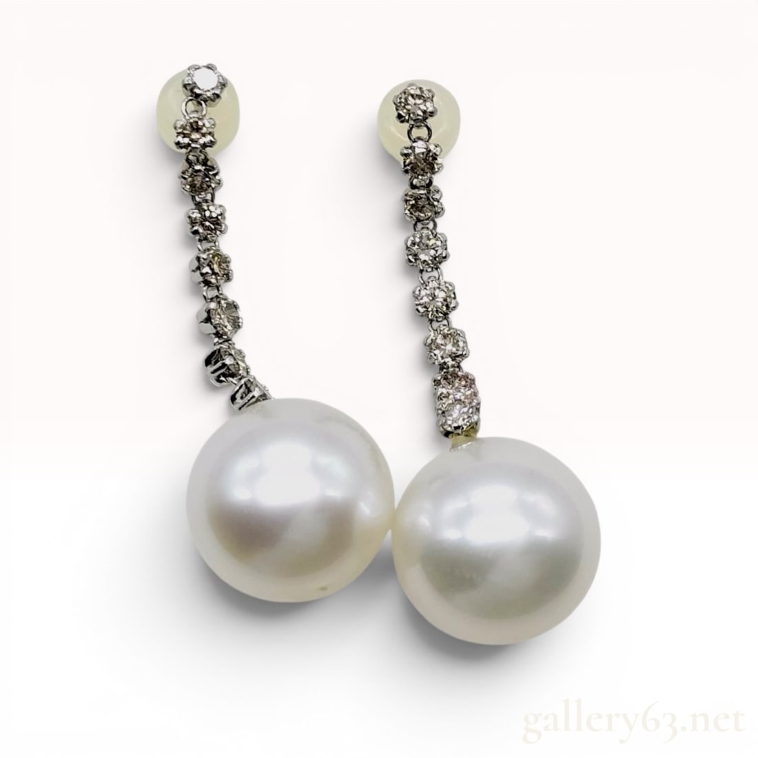 A Stunning Pair of Platinum Diamond and South Sea Pearl Linear Drop Earrings: A matched pair of contemporary platinum linear drop earrings featuring large white South Sea cultured pearls. Each earring consists of six round brilliant-cut diamonds in individual four-prong setting