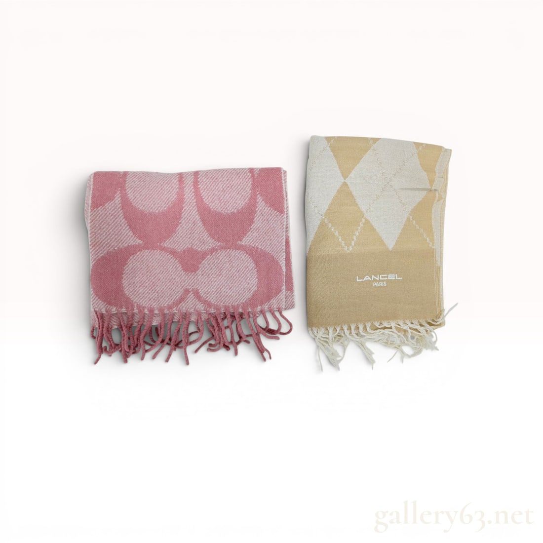 Two Designer Mufflers including Coach Signature Oversized Muffler and Lancel Argyle Scarf: Two designer mufflers featuring a Coach Signature Oversized Muffler and a Lancel Paris argyle scarf. The Coach muffler is composed of a tonal pink 90% wool and 10% cashmere blend with a large-scale mo