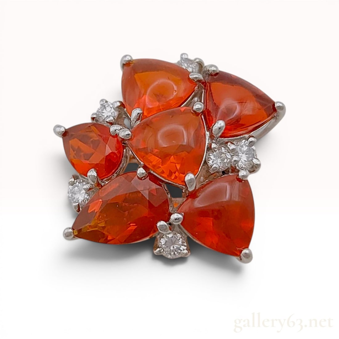 Fire Opal and Diamond Platinum Floral Cluster Pendant: A platinum floral cluster pendant featuring five prong-set orange fire opals in pear and trillion cuts accented by round brilliant-cut diamonds. The slide-style mounting is crafted in 900 platinum wit