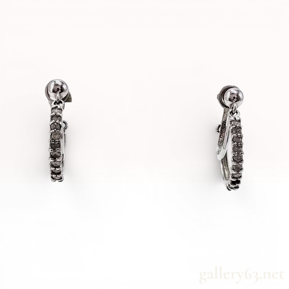 A Pair of 14K White Gold and Diamond Screw-Back Hoop Earrings: A matched pair of white gold and diamond hoop-style earrings. Each earring features a row of eleven small, round-cut diamonds channel-set along the forward-facing curve of the hoop. 1.9 grams total we