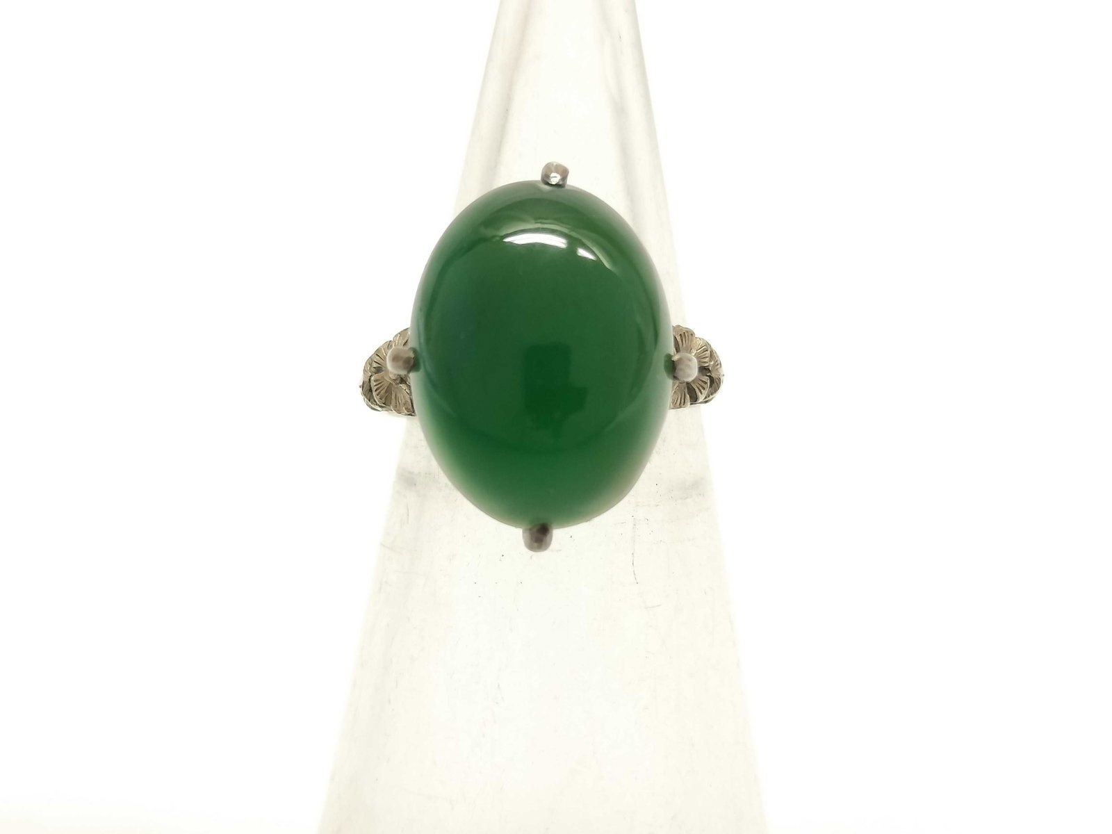 Sterling Silver Floral Motif Cocktail Ring: Vintage-style sterling silver cocktail ring featuring a large oval green cabochon stone in a four-prong basket setting. The ring is detailed with ornate floral and foliate cast shoulders leading to an